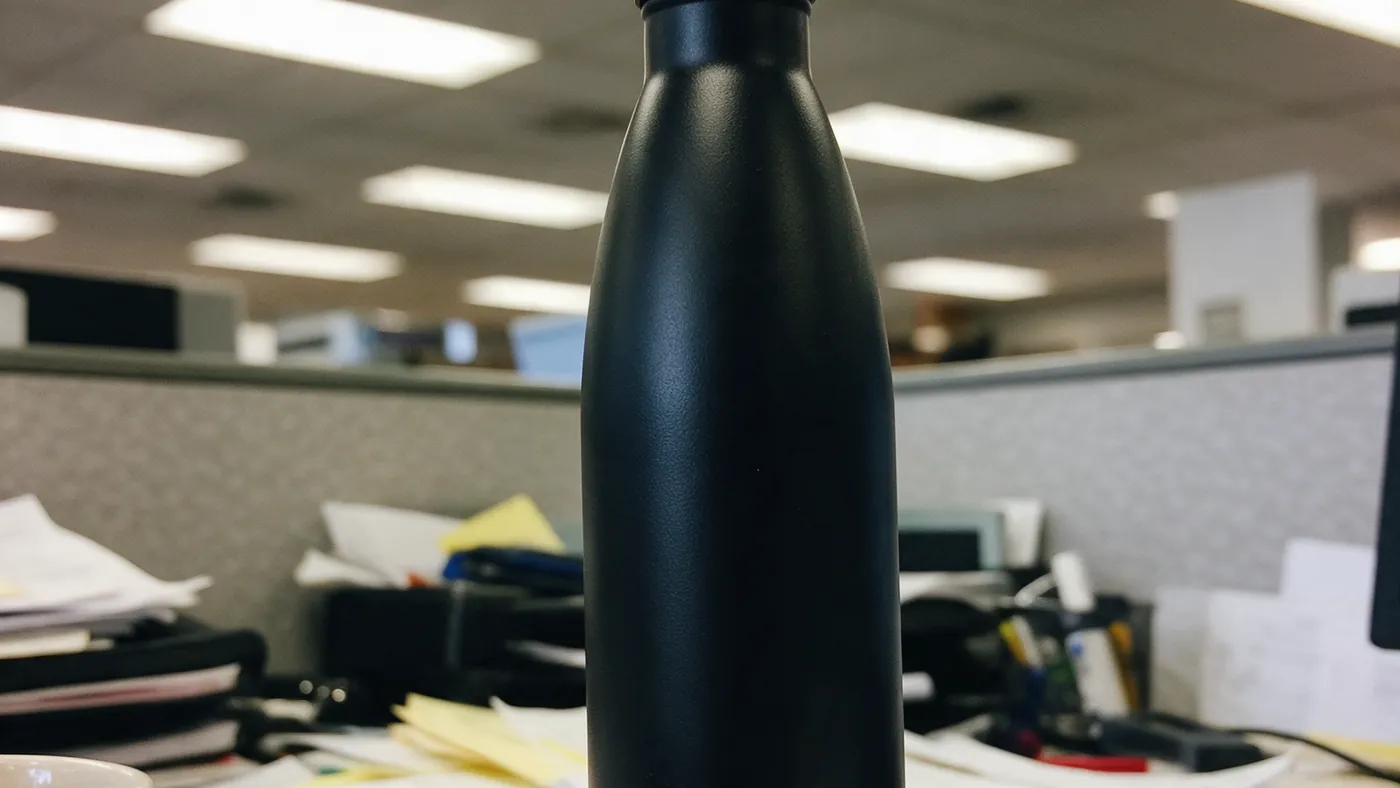 The photo we were sent: a phone snapshot of a matte black bottle on an office desk